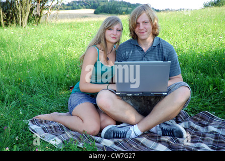 Jeune couple amoureux, assis sur une prairie avec coffre Banque D'Images