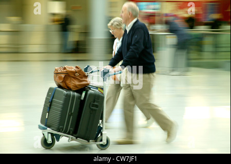 Elder couple avec leurs bagages sur un chariot à l'aéroport. Banque D'Images