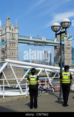 Vue arrière deux bureaux de police métropolitains une policière et un policier en patrouille à pied d'été près de Tower Bridge Southwark Londres Angleterre Royaume-Uni Banque D'Images