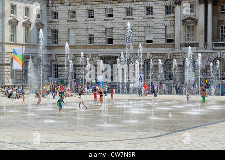 Les familles profitant de la cour intérieure fontaines dansantes à Somerset House sur une chaude journée d'été du côté sud de la Strand London England UK Banque D'Images