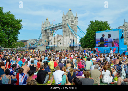 Une foule de gens s'assoient sur l'herbe pour regarder les Jeux olympiques de Londres 2012 Événement de sport de télévision grand écran de télévision en plein air dans Potters Fields Park Southwark Angleterre Royaume-Uni Banque D'Images