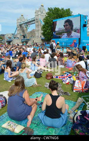 Une foule de gens s'assoient sur l'herbe pour regarder les Jeux olympiques de Londres 2012 Événement de sport de télévision grand écran de télévision en plein air dans Potters Fields Park Southwark Angleterre Royaume-Uni Banque D'Images