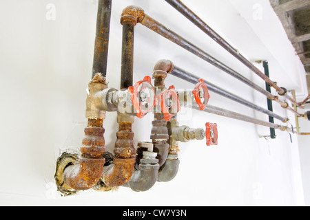 L'eau de refroidissement chauffage vieux tuyaux de plomberie avec soupapes sur le mur blanc Banque D'Images