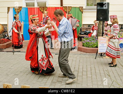 Le Bélarus groupe folklorique chante sur la Suvorova street à Vitebsk. Le spectateur danse avec la comédienne. Banque D'Images