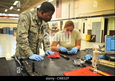 Les aviateurs senior de la Force aérienne des États-Unis seront Sinclair et Melissa Moreno, 27e Escadron de maintenance des opérations spéciales, nettoyer et vérifier les composants des armes dans l'atelier d'armement de la base aérienne de Cannon, N.M., le 14 août 2012. Les troupes d'armement se prennent à Cannon pour démonter, nettoyer, luber et inspecter les armes de leur avion. Banque D'Images