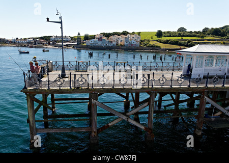 Deux hommes de la pêche la fin de Swanage pier avec des logements modernes à Pevril Point dans l'arrière-plan. Banque D'Images