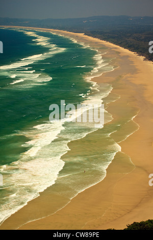 Vagues triple rouleau sur une plage de sable déserte Byron Bay en Nouvelle Galles du sud, au Banque D'Images