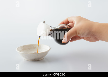 La main de jeter de l'huile dans un bol Banque D'Images