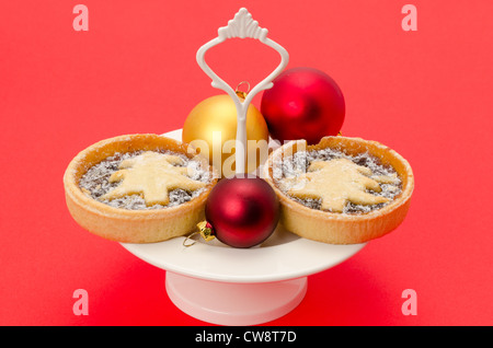 Fêtes de Noël ou petits pâtés fait maison et placé sur un plat à gâteau - studio photo avec un fond rouge Banque D'Images