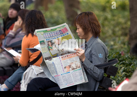 Hong Kong, woman reading a newspaper Banque D'Images