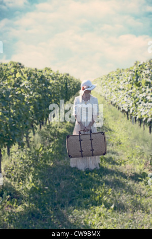 Une femme en blanc, robe victorienne en balade entre vignobles Banque D'Images