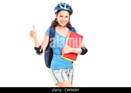 Une fille sur rouleaux holding notebooks et giving thumb up isolés contre fond blanc Banque D'Images