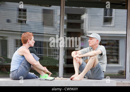 La femme et l'homme parle, assis sur un banc à l'extérieur. Banque D'Images