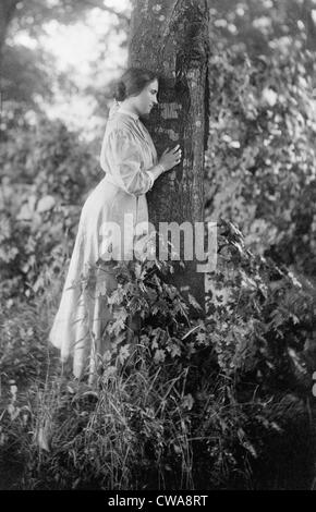 Helen Keller (1880-1968), aveugle et sourde depuis l'âge de 2 ans, debout par arbre, en 1907. Banque D'Images