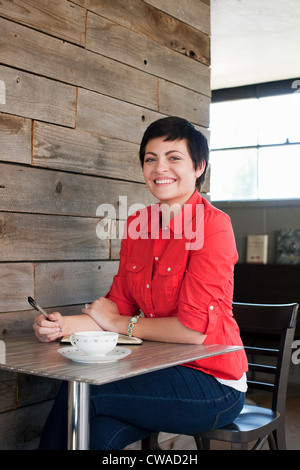 Woman wearing red shirt assis dans un café, portrait Banque D'Images