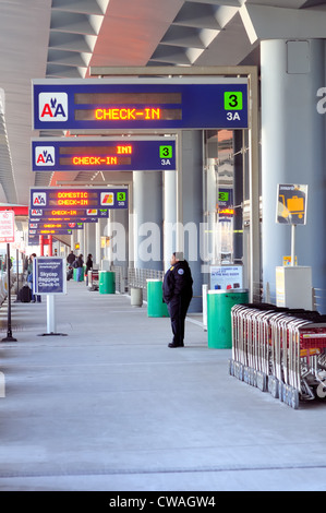 Gardien de sécurité se tient sous les panneaux guider les passagers terminaux de départ de Chicago O'Hare International Airport. Chicago, Illinois, USA. Banque D'Images
