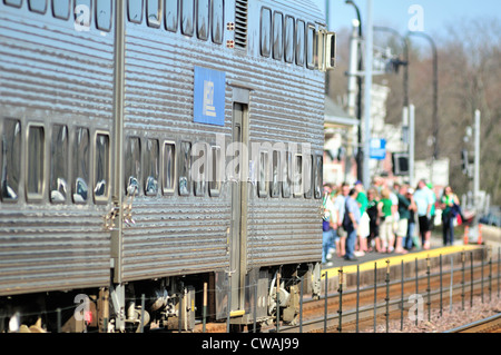 Train de banlieue Metra station Illinois Genève, le jour de la Saint Patrick plate-forme bondée de passagers en direction de Chicago. Genève, Illinois, USA. Banque D'Images