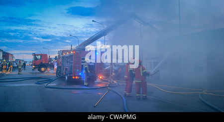 Les pompiers en action les flammes de pulvérisation.atelier de réparation automobile en feu dans la banlieue de Reykjavik, Islande Banque D'Images