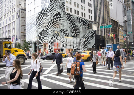 Les gens traversent la 5e Avenue à la 57e rue, avec l'arrêt de l'œil extérieur de la Louis Vuitton flagship store à l'arrière-plan. Banque D'Images
