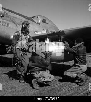 Un pilote de chasse de Tuskegee et deux aviateurs ajuster une 75 gallon externe réservoir goutte sur l'aile d'un P-51D Mustang, Banque D'Images