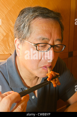 Homme mange asiatique pieds de poulet, plat populaire servi de dim sum, brunch chinois. Banque D'Images