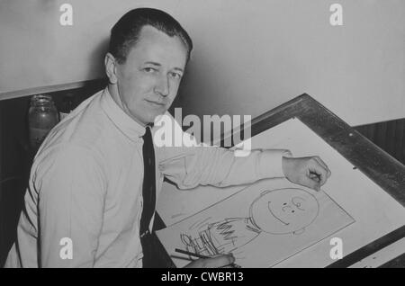 Charles Schulz (1922-2000), assis à table à dessin avec le dessin de Charlie Brown, l'un de ses caractères d'arachides. 1956. Banque D'Images