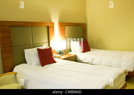 Chambre d'hôtel avec deux lits couverts par literie blanche dans la nuit Banque D'Images