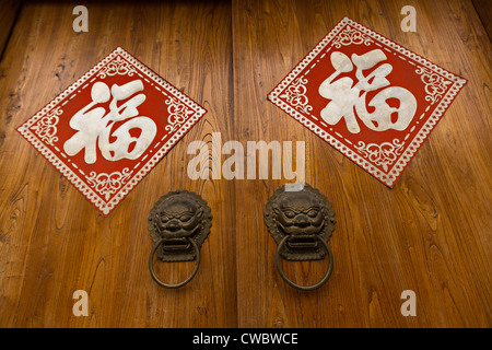 Porte traditionnelle chinoise avec des lampions rouges et bonne chance signes dans le district de Wudaoying hutong restauré à Beijing, Chine Banque D'Images