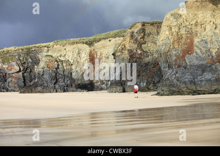 Homme marche le long de la base des falaises bordant la plage Gwithian, St Ives Bay, Cornwall, England, UK Banque D'Images