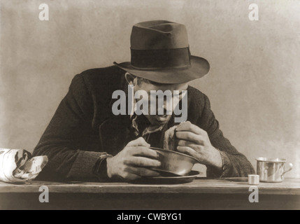 Homme affamé avec son repas de pain et de la soupe à une soupe populaire de la ville de New York au cours de la Grande Dépression. Son fedora et maintenant Banque D'Images