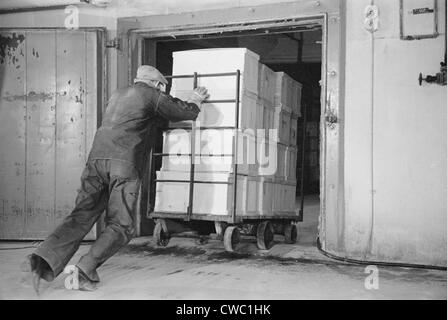 Pousse un travailleur lourd chariot de paniers oeufs dans un entrepôt frigorifique, Jersey City, New Jersey en avril 1939. Banque D'Images