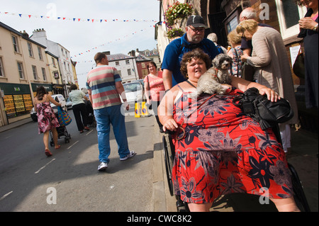 Femme est poussée en fauteuil roulant avec chien sur la rue lors du Festival de Jazz 2012 Brecon Banque D'Images