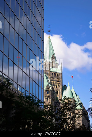 Le Parlement canadien Confederation Building vu derrière un édifice moderne en verre à Ottawa, Canada. Banque D'Images