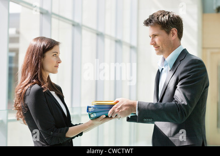Les fichiers d'affaires donnant son collègue dans un bureau Banque D'Images