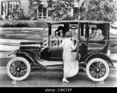 Vue latérale d'une Ford sedan avec quatre passagers et une femme entre sur le côté conducteur, vers 1923 Banque D'Images