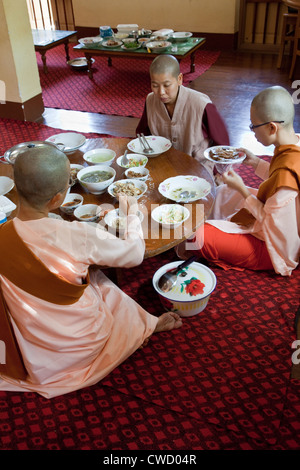 Le Myanmar, Birmanie. Zayar Thein Gyi Antiq, près de Mandalay. Les nonnes bouddhistes prenant le déjeuner, assis sur le plancher. Banque D'Images