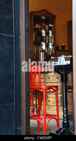 Un tabouret rouge dans un café-bar considéré de l'extérieur Banque D'Images