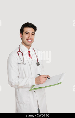 Portrait of a smiling Indian male doctor holding medical un graphique sur fond gris clair Banque D'Images