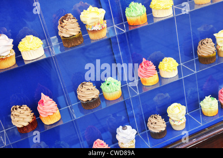 Délicieux cup cakes colorés en fenêtre shop Banque D'Images