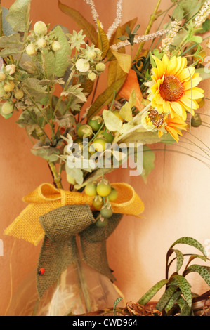 Un pot en verre avec tournesols jaunes et d'autres plantes décoratives Banque D'Images