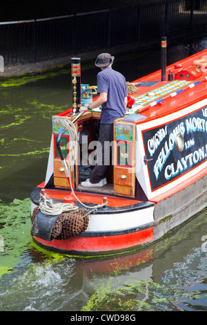 Homme sur Barge naviguant Regents Canal grâce à Camden Lock à London UK Banque D'Images