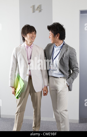 Deux hommes d'affaires parlant à l'ascenseur du hall Banque D'Images