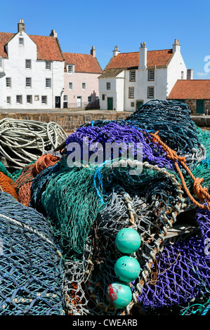 Pittenweem, East Neuk de Fife, Scotland, UK. Les filets de pêche empilés sur le quai avec des maisons d'un style typique de la région. Banque D'Images