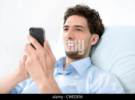 Jeune homme séduisant à l'aide de smart phone mobile moderne. Studio shot. Banque D'Images