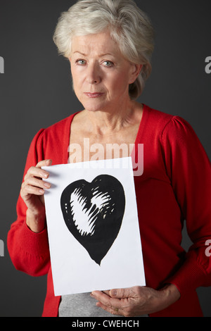 Senior woman holding dessin à l'encre du coeur Banque D'Images