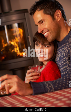 Couple assis sur un canapé à regarder la télévision par Cheminée Banque D'Images