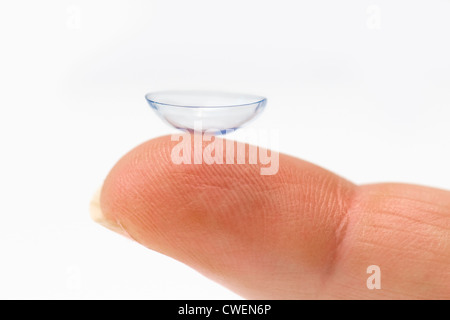 Close up de lentilles de contact unique sur Caucasian womans finger against white background Banque D'Images