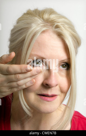 Femme aux cheveux blonds sur le point d'insérer la lentille de contact Banque D'Images