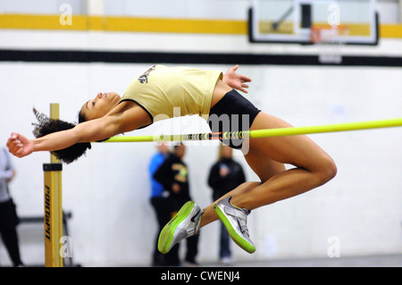 Saut en hauteur Femmes athlètes efface la barre sur un saut en hauteur durant une école d'athlétisme à l'intérieur. USA. Banque D'Images