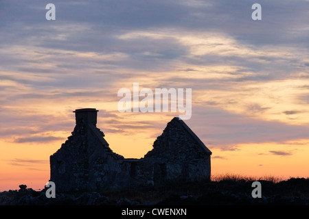 Cottage en ruine silhouetté contre le ciel au coucher du soleil. Près de Beal une Daingin, Connemara, comté de Galway, Irlande, Connaught. Banque D'Images